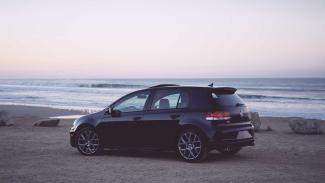 Volkswagen golf on the beach with ocean in background.